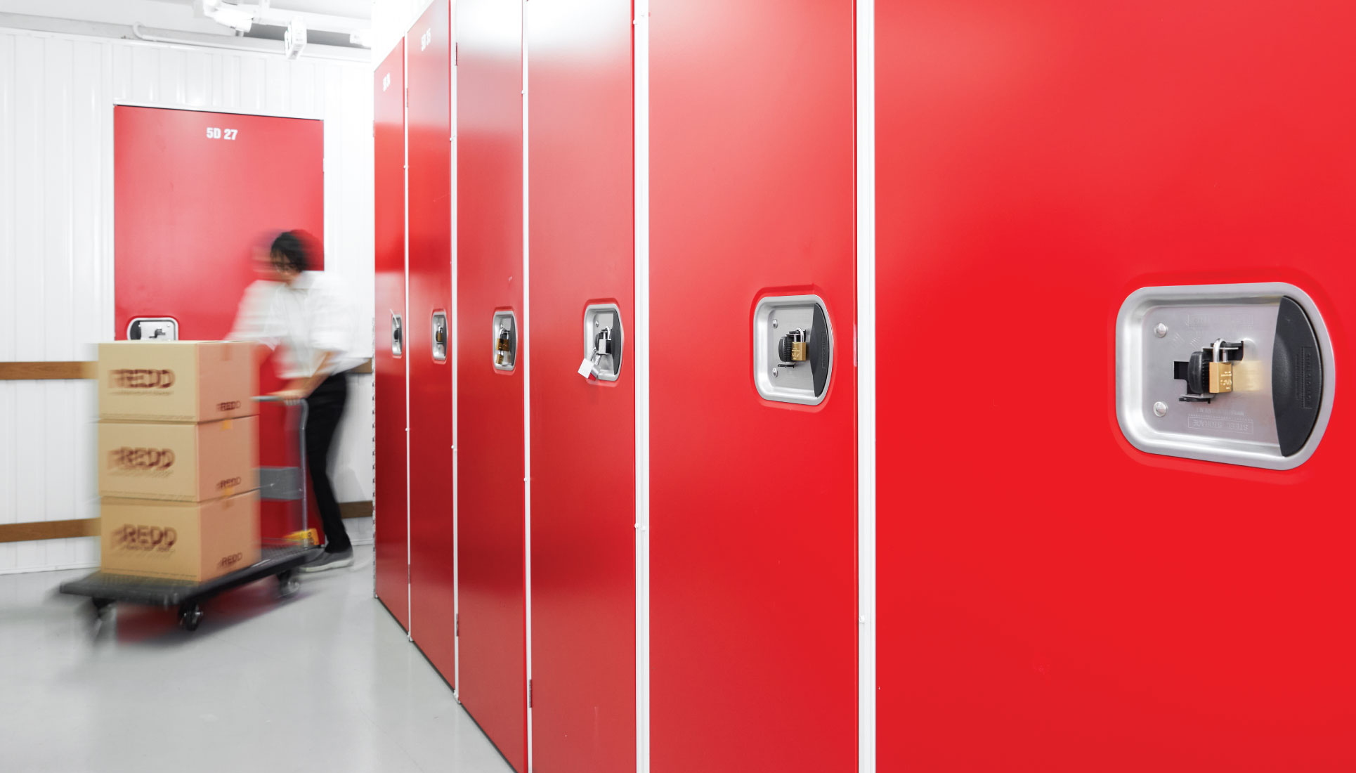 Wall of red REDD mobile racking units, with boxes arriving on a trolley