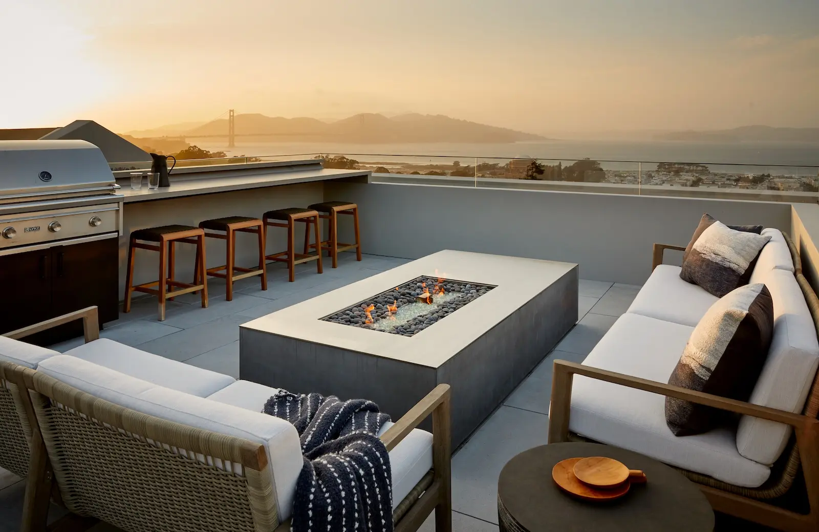 Rooftop terrace with fire pit and outdoor kitchen overlooking the Golden Gate Bridge at dusk