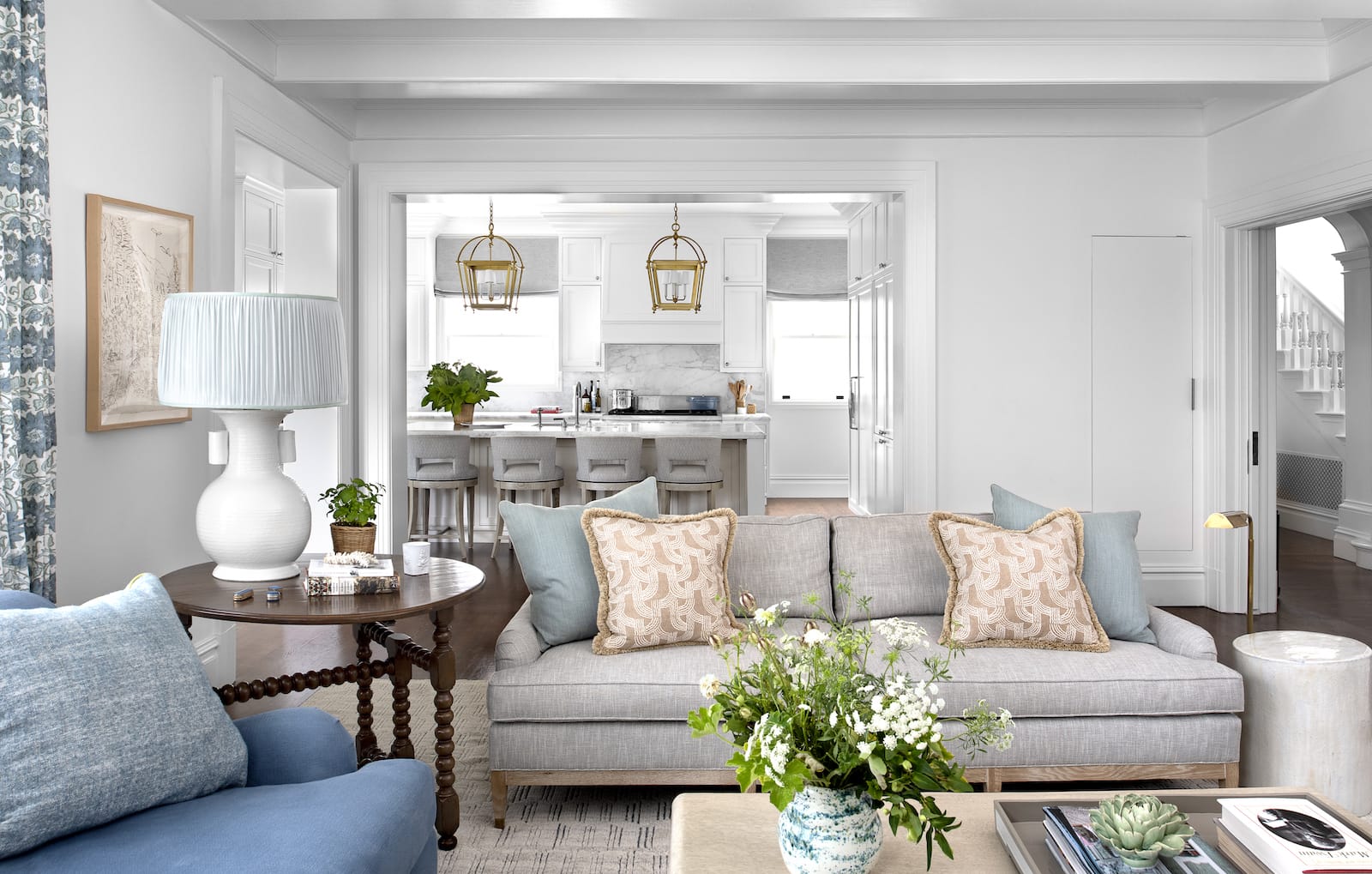 Presidio Terrace living room in soft whites, opening through to a lantern-lit kitchen