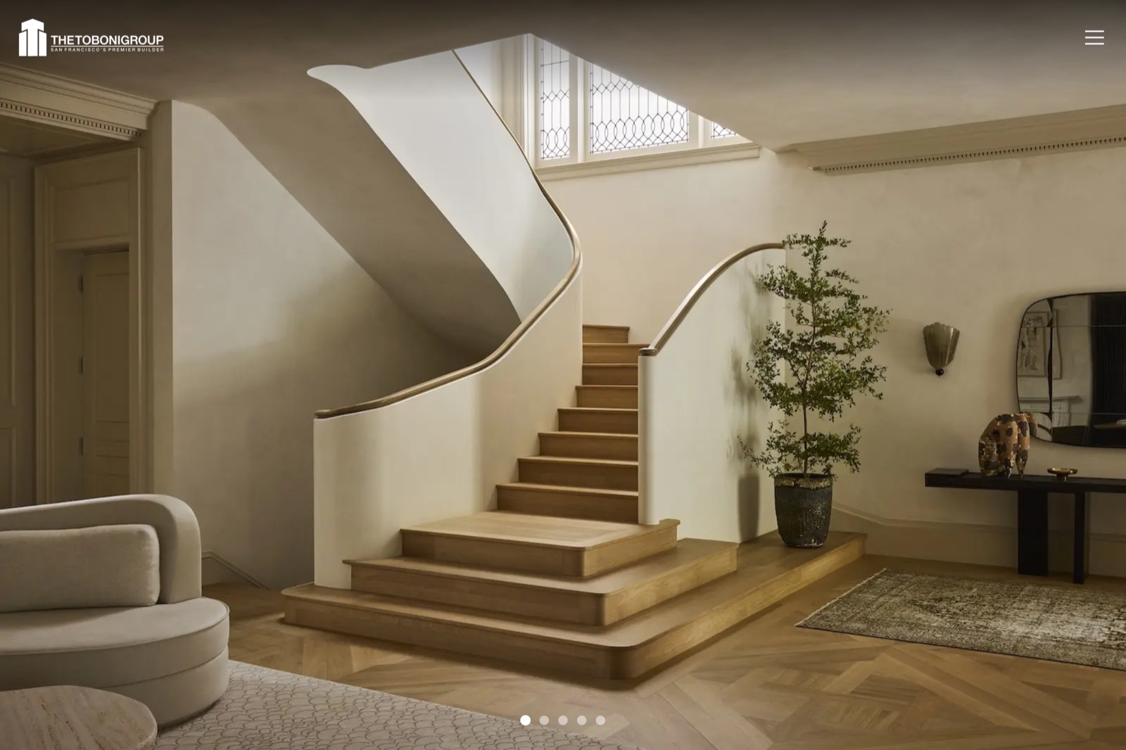 The Toboni Group homepage — full-bleed photograph of a curved oak staircase with only a logo and menu