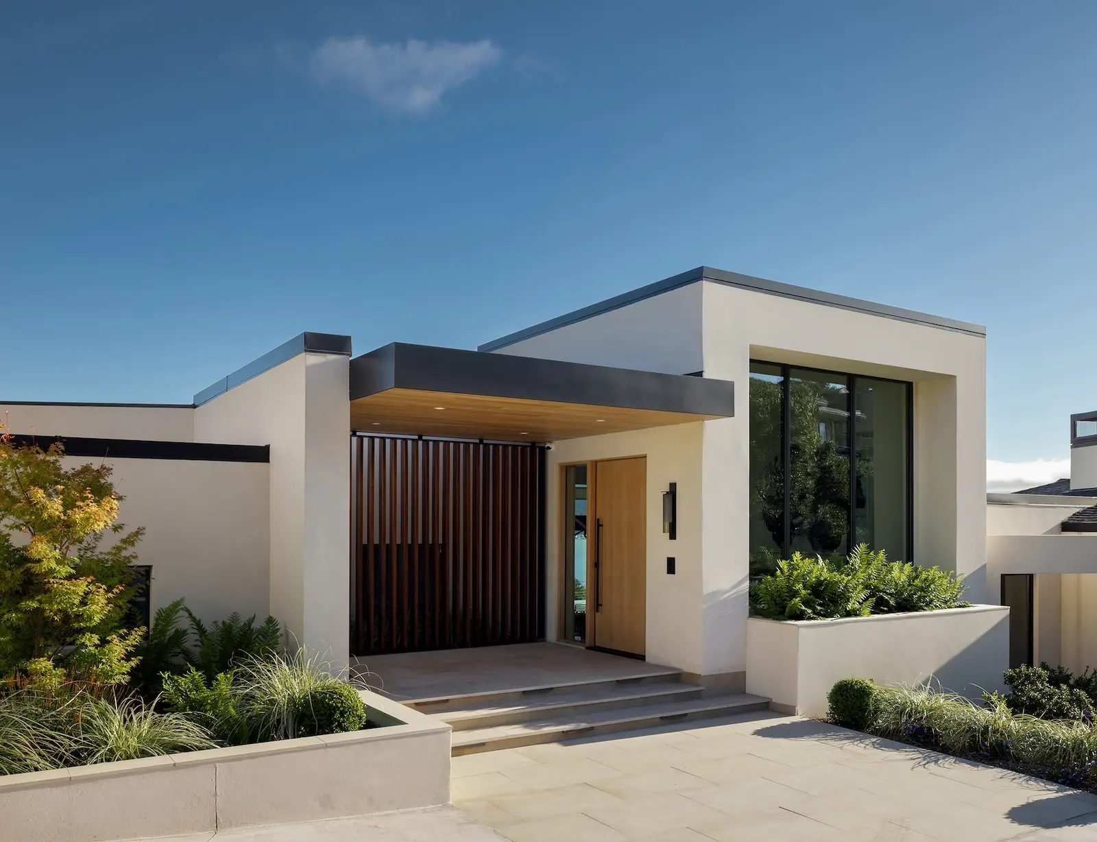 Modern flat-roofed Tiburon home with slatted wood entry screen and oak front door