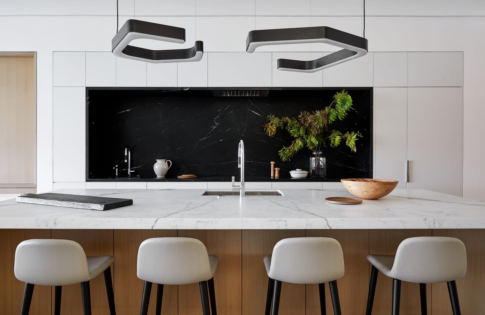 Book-matched arabescato marble kitchen with brass fixtures and articulated pendant