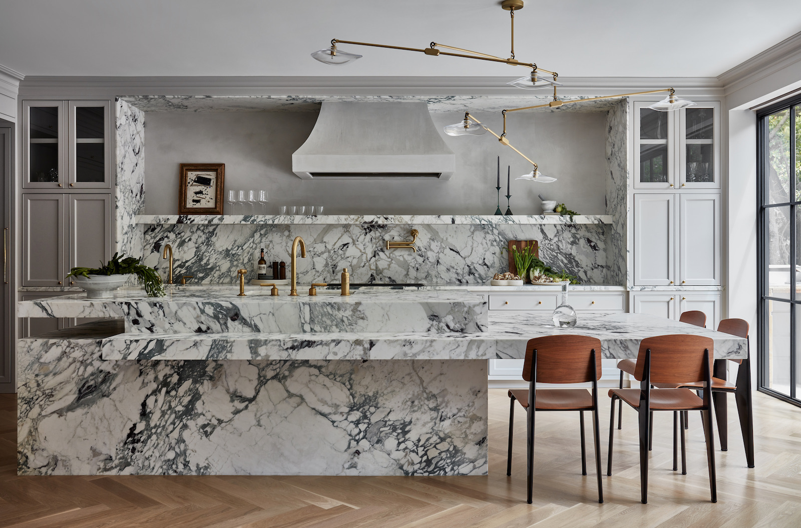 Minimal white kitchen with black soapstone backsplash and sculptural pendants